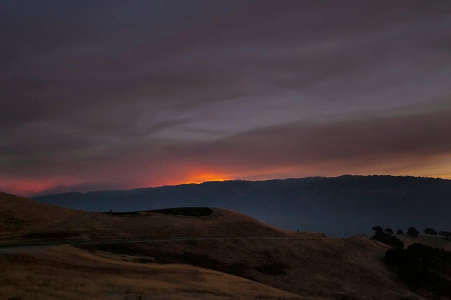 Wildfire glow behind darkened California hills at night